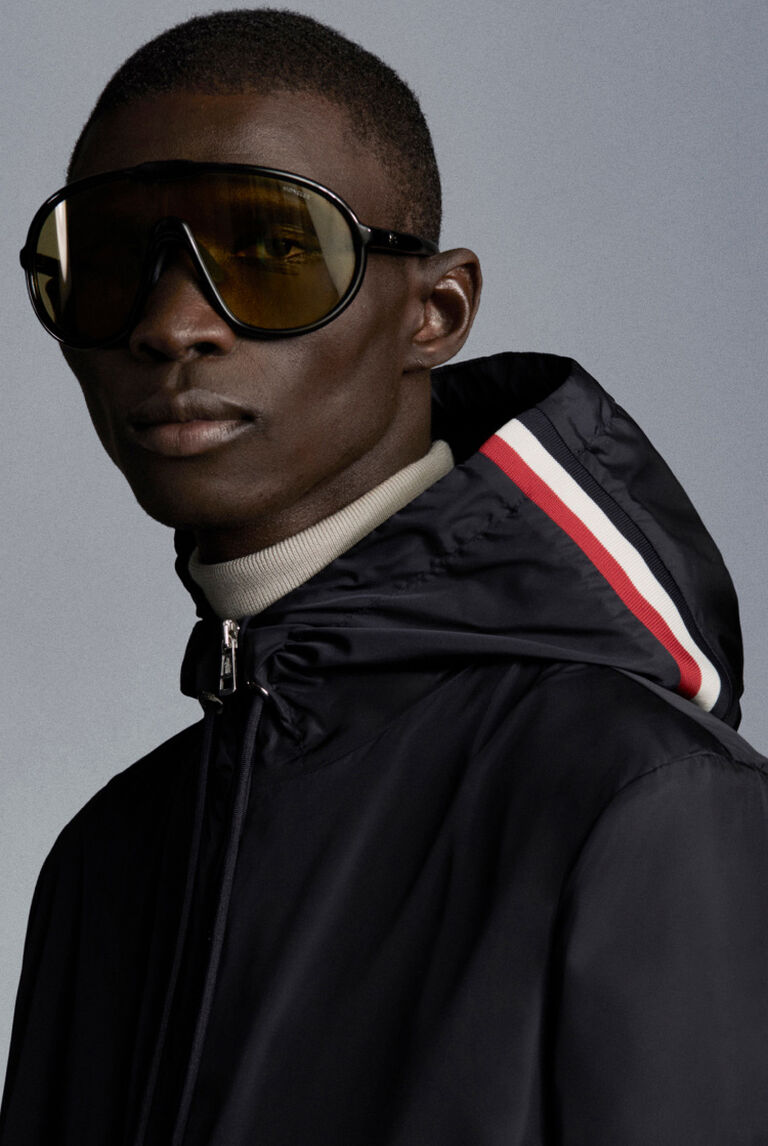 One man wears a Moncler blue anorak and sunglasses
